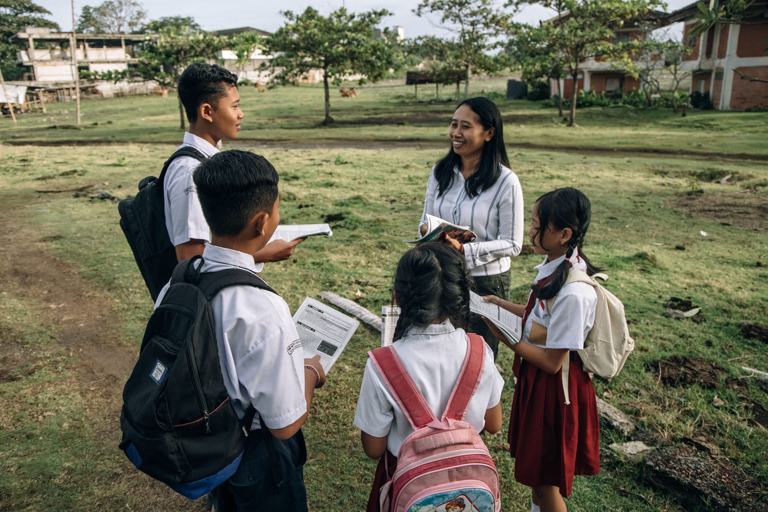 A group of students in school uniforms learning outdoors with their teacher.